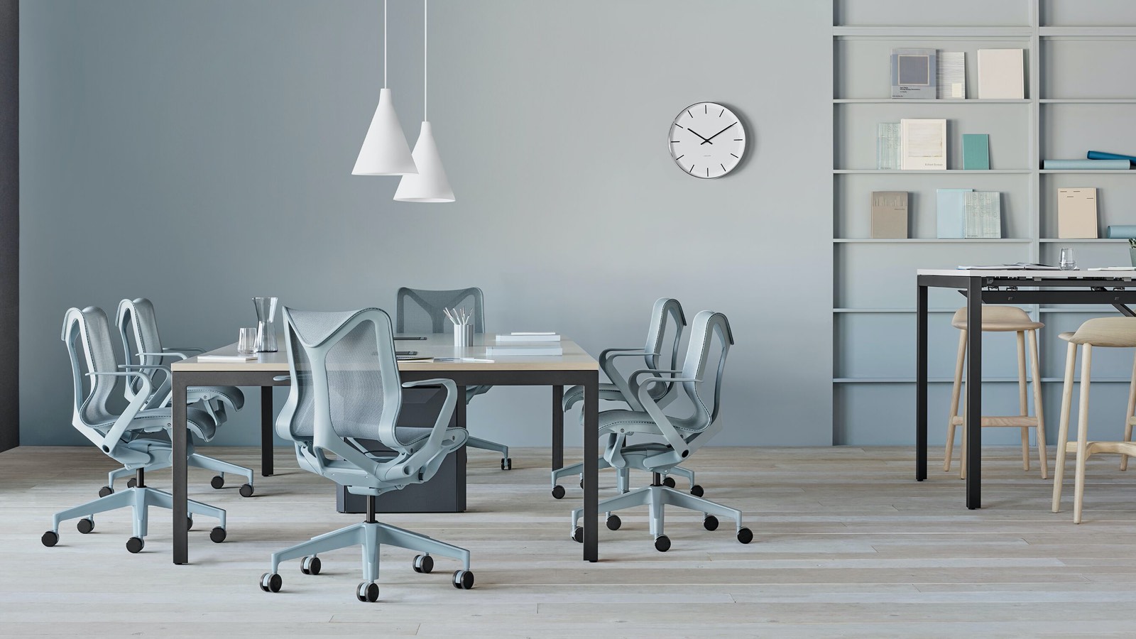 Several low-back Cosm Chairs in light blue glacier finish surround a Layout Studio conference table in an airy open office space. Select to search for a Herman Miller dealer.